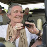 A family in a safari jeep in a wildlife reserve, a seniorwoman with binoculars.